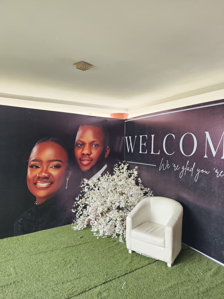Deep burgundy printed wedding welcome backdrop featuring the couple's portraits