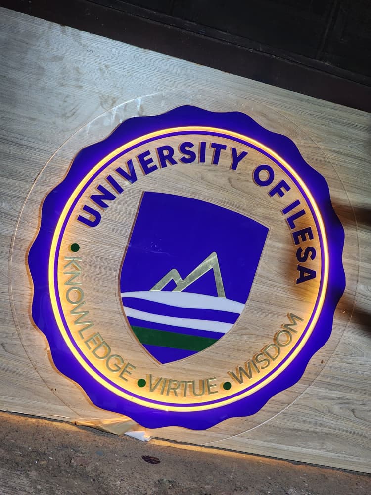 Backlit University of Ilesa crest with gold Knowledge, Virtue, Wisdom motto ring