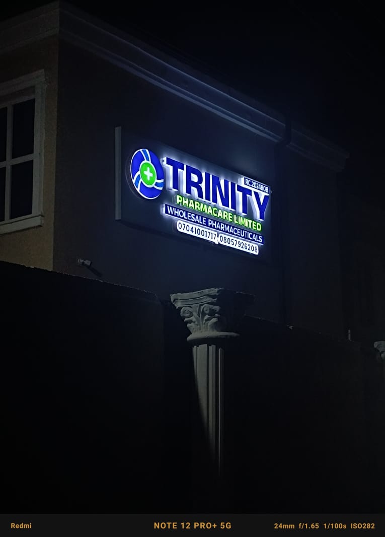 Illuminated Trinity Pharmacare facade signage glowing on building wall at night