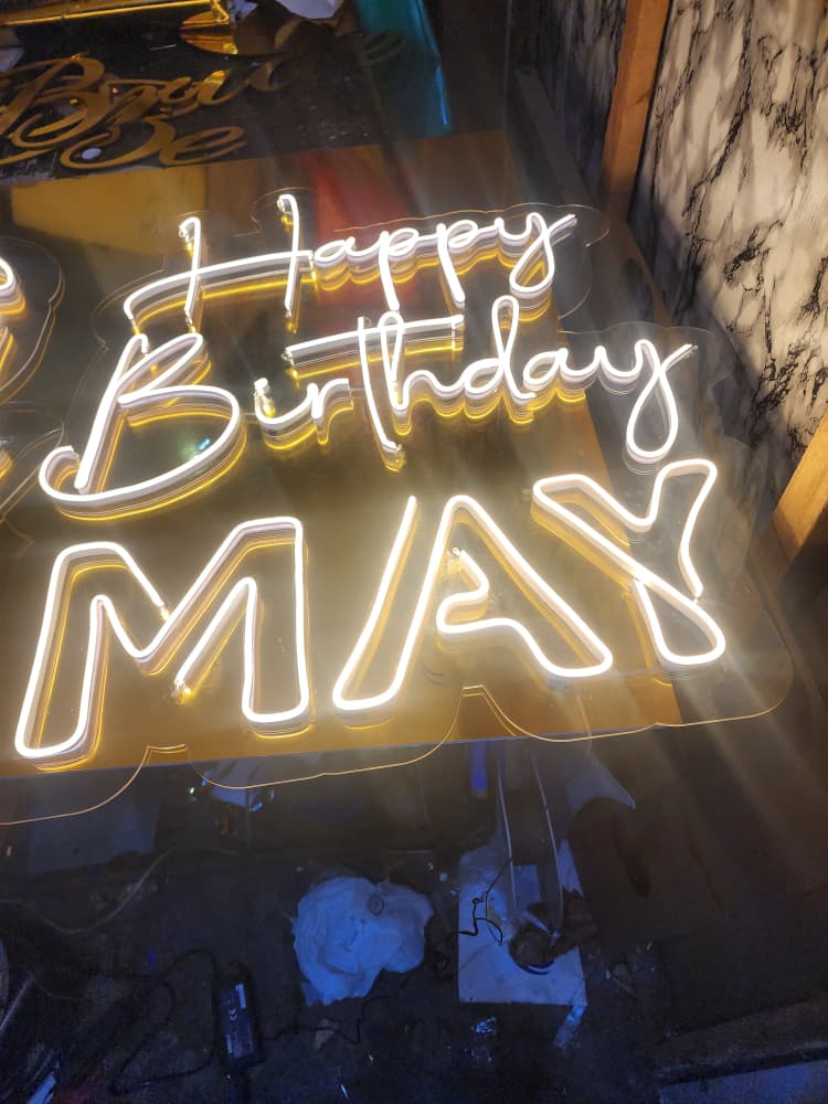 Warm gold custom neon sign reading Happy Birthday May in flowing script and block lettering