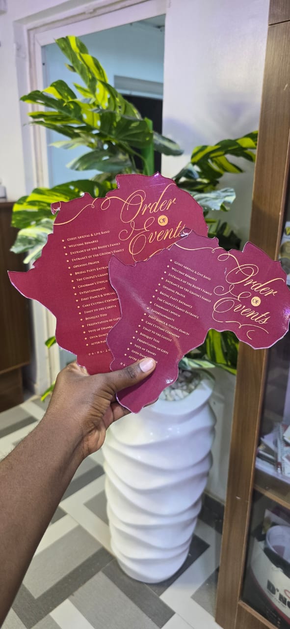 Die-cut Africa-shaped wedding order of events card in burgundy with gold foil calligraphy