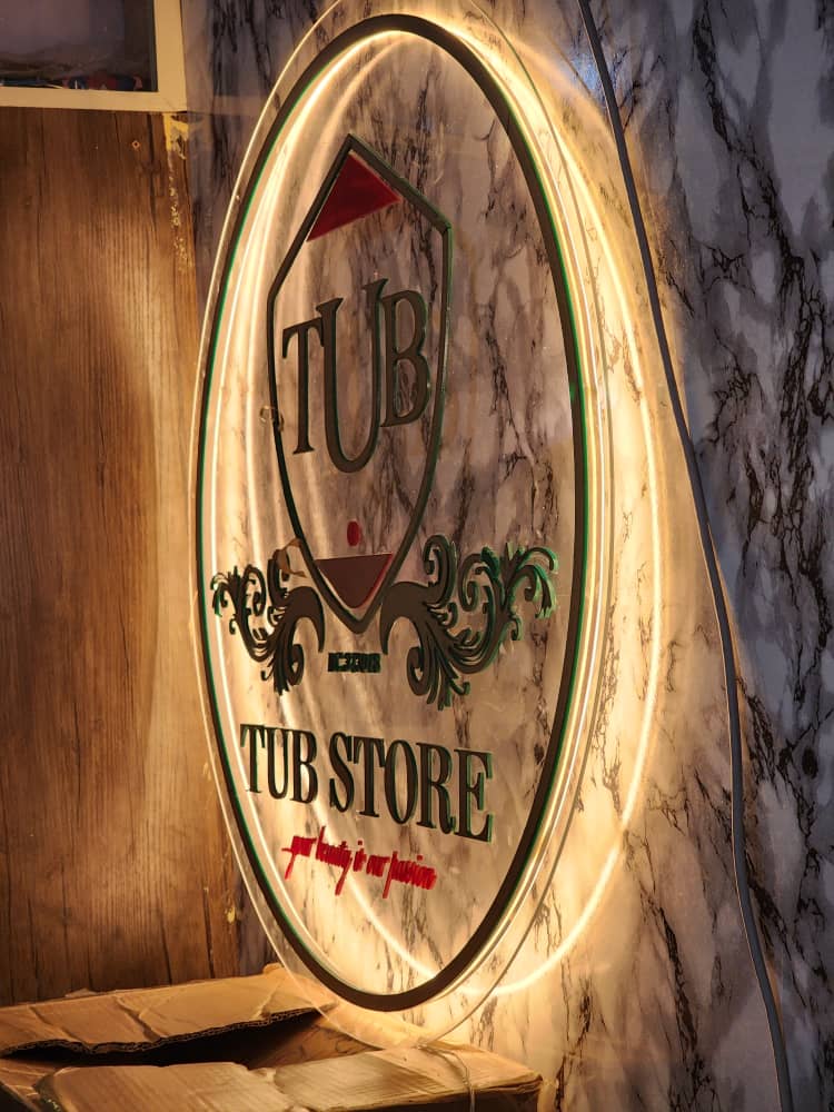Oval halo-lit TUB Store beauty boutique signage with crest and filigree on marble wall