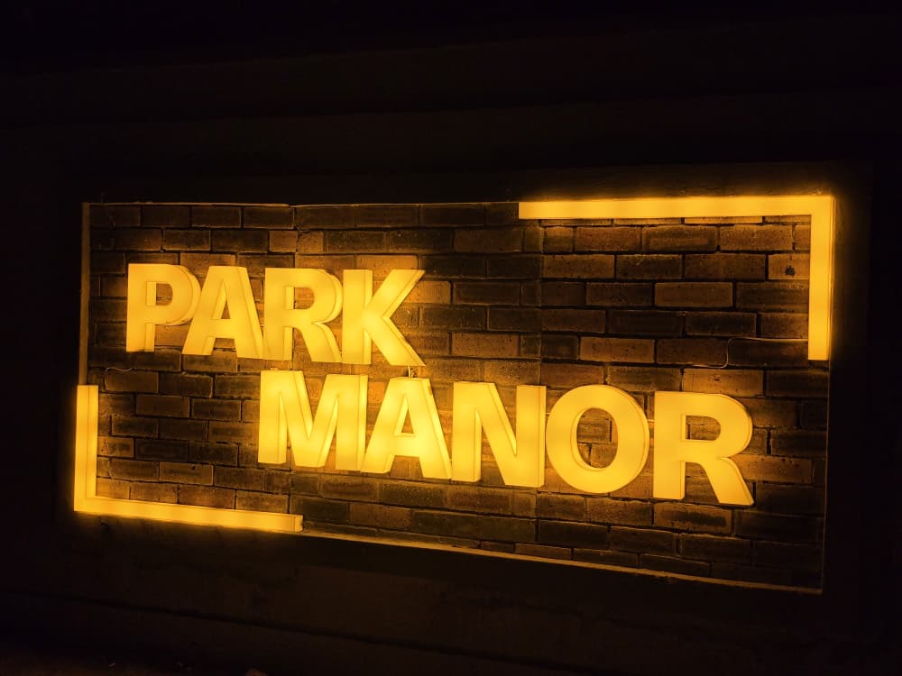 Warm backlit Park Manor 3D lettering mounted on a rustic brick wall